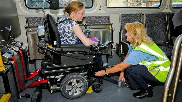 Transit operator assisting a rider using a wheelchair inside an accessible vehicle